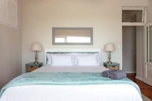 a bedroom with a large white bed with two lamps at Paradise Views Vacation Home in Cape Town