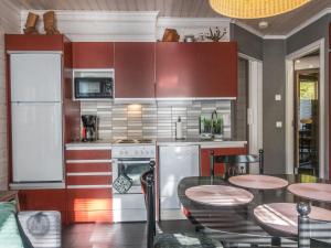 a kitchen with red cabinets and a table and chairs at Holiday Home Kuurankuksa a by Interhome in Sirkka