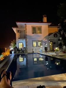 uma pessoa sentada em frente a uma casa com uma piscina em Gemütliche Villa mit Pool, extravagant, luxuriös em Ula