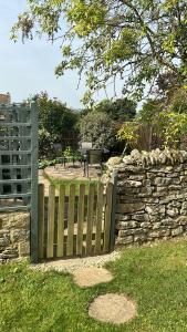 a wooden fence next to a stone wall at Charming Cottage, Great Rissington, Cotswolds in Great Rissington