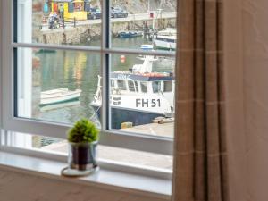 a window with a view of a boat in a harbor at Apartment Lighthouse View by Interhome in Mevagissey