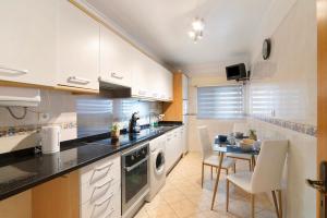 a kitchen with white cabinets and a table with chairs at Apartamento do Sol in Albufeira