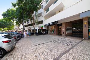 a street with cars parked in front of a building at Apartamento do Sol in Albufeira