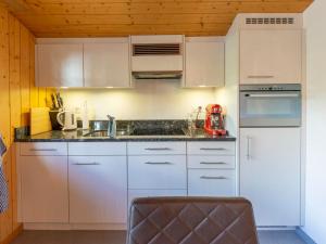 a kitchen with white cabinets and a red appliance at Apartment Uf dr Fuhre by Interhome in Adelboden