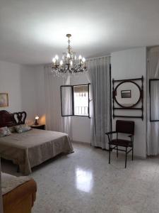 1 dormitorio con 1 cama, 1 silla y 1 lámpara de araña en Casa Mis Abuelos, en Priego de Córdoba