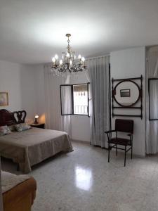una camera da letto con un letto, una sedia e un lampadario di Casa Mis Abuelos a Priego de Córdoba