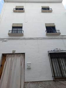 un edificio blanco con tres ventanas y una puerta en Casa Mis Abuelos, en Priego de Córdoba