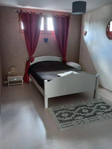 una camera da letto con un letto con tende viola e un tappeto di Pont-de-poitte: Appart'Alice a Pont-de-Poitte