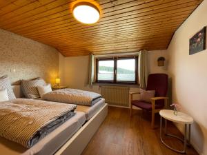 a room with two beds and a chair and a window at Holiday Home Landhaus Klara by Interhome in Eisenbach