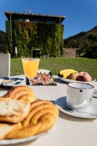 una mesa con platos de pan y un vaso de zumo de naranja en Fagoaga dorretxea en Ergoyen