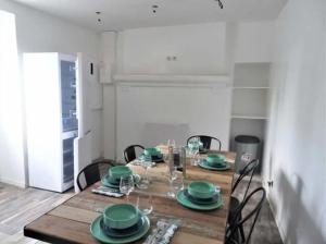 uma sala de jantar com uma mesa de madeira com pratos verdes em *Studio 1* Avenue Baudin - DABNB em Limoges