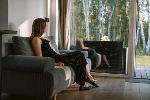 una mujer sentada en un sofá mirando por la ventana a un piano en Czas na Las, en Żarnowska