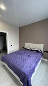 a bedroom with a large bed with a purple blanket at Cozy 2 room apartment in city center in Almaty