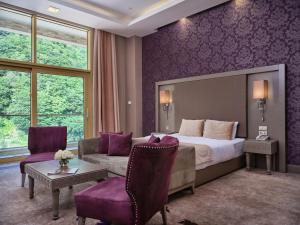 فندق منتجع قفقاز توفنداغ مونتاين  في غابالا: غرفه فندقيه بسرير واريكه