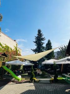 a patio with umbrellas and a green slide at Pensiunea Curtea Bavareza in Târgu-Mureş