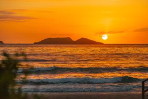 a sunset on the beach with the sun setting over the ocean at Slaviero Ingleses Convention in Florianópolis