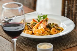 a plate of shrimp pasta and a glass of wine at Slaviero Ingleses Convention in Florianópolis