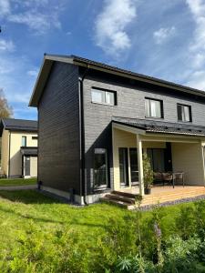a black house with a patio and grass at Moderni paritalo lähellä lentokenttää, free parking, sauna in Vantaa