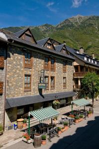 ein Gebäude mit Bänken und Tischen davor in der Unterkunft Hotel Avenida Benasque in Benasque