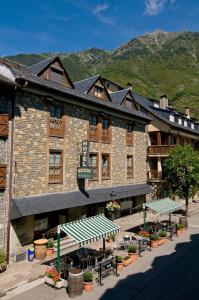 a building with benches and tables in front of it at Hotel Avenida Benasque in Benasque