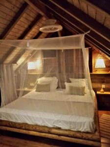 a bedroom with a white canopy bed with pillows at PURA VIDA Lodge Cabane perchée in Sainte-Rose