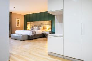 Un dormitorio con una cama y una pared verde. en WL Hotel Maputo - City Center, en Maputo