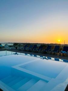 uma piscina com cadeiras e o pôr-do-sol ao fundo em Lc Apartments - Sunshine em Santa Maria