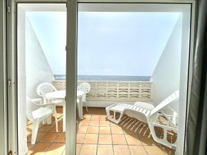 balcón con mesa, sillas y vistas al océano en Oceanfront apartment a few meters from the beach, en Tamaduste