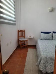 1 dormitorio con 1 cama, 1 silla y 1 ventana en Casa Natalia., en Taibique