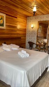 a bedroom with a large white bed with two towels at Cabanas Por do Sol in Urubici