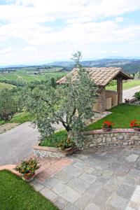 a stone pathway leading to a house with a tree and flowers at AGRITURISMO VICOLABATE in San Casciano in Val di Pesa