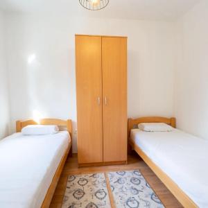 two twin beds in a room with a cabinet at Apartman Lux Blidinje in Blidinje