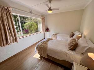 1 dormitorio con 2 camas y ventana en Berg Escape Bottlebrush - Spacious Luxury Family Home en Winterton