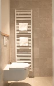 a bathroom with a toilet and towels on a towel rack at Appartement N05 Bakboord & Stuurboord in Oost-Vlieland