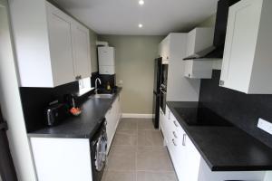 a kitchen with white cabinets and black counter tops at Plawsworth Hall Serviced Cottages and Apartments in Durham