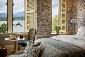 a bedroom with a bed and a window with a boat in the water at Langdale Chase Hotel in Windermere