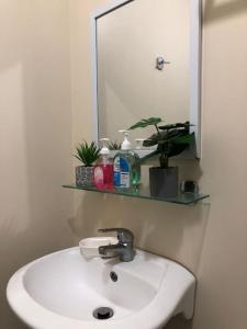 La salle de bains est pourvue d'un lavabo blanc et d'un miroir. dans l'établissement Davao BellaDom Staycation, à Davao