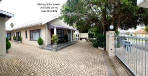 a house with a fence in front of a brick driveway at MeTime Guesthouse & Self catering in Hartenbos