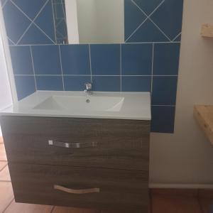 a bathroom with a sink and a blue tiled wall at Bungalow cocodile in Sainte-Anne