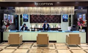 una zona reception di un hotel con due persone in piedi a un bancone di City Tower Hotel a Fujaira