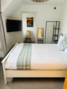 Lochaline Hotel في Lochaline: غرفة نوم بسرير كنج وتلفزيون