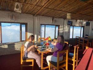 a man and woman sitting at a table in a restaurant at Panoramic View Guest House Sarangkot in Pokhara
