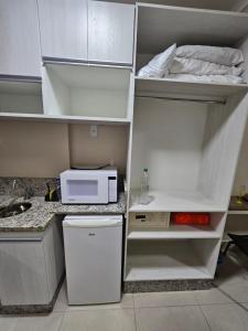 eine Küche mit einem weißen Kühlschrank und einer Mikrowelle in der Unterkunft Spazzio diRoma com acesso ao Acqua Park, Caldas Novas in Caldas Novas
