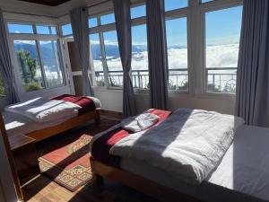 two beds in a room with a window at Panoramic View Guest House Sarangkot in Pokhara