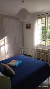 um quarto com uma cama com um edredão azul e uma janela em LA MAISON DU BONHEUR em Velleron