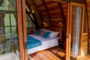 1 dormitorio con 1 cama en una casa de madera en Sacha Urco Lodge y Bosque Protector, en Mindo