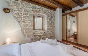 a bedroom with a stone wall and a bed with towels at Holiday Houses Luan in Poreč