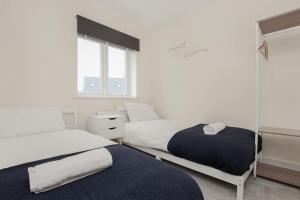 two beds in a room with white walls and windows at Luxury Colchester House in Colchester