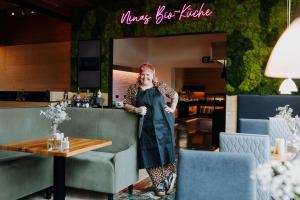 a woman standing in front of a table at Bio-Berghotel Ifenblick in Balderschwang