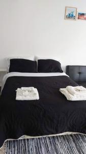 1 dormitorio con 1 cama negra y 2 toallas en Encanto Fueguino calido centrico wifi para dos en Ushuaia